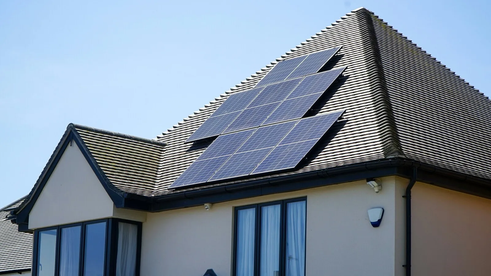A pitched UK house roof with solar panels installed on the south-facing side