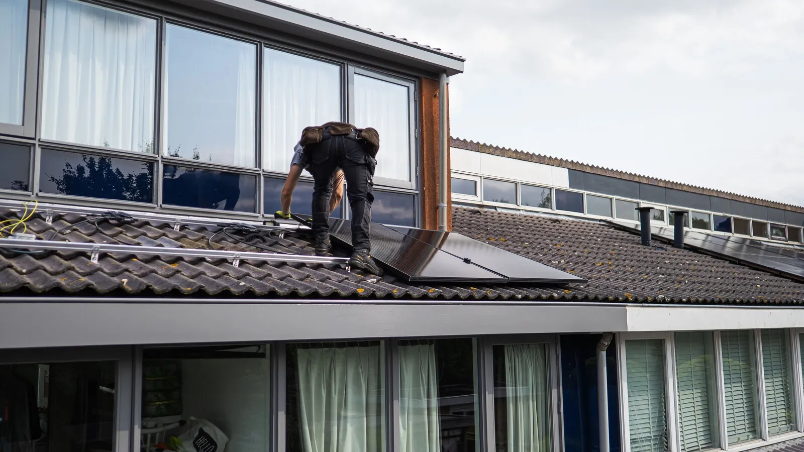An installer fitting solar panels onto a tiled UK residential roof